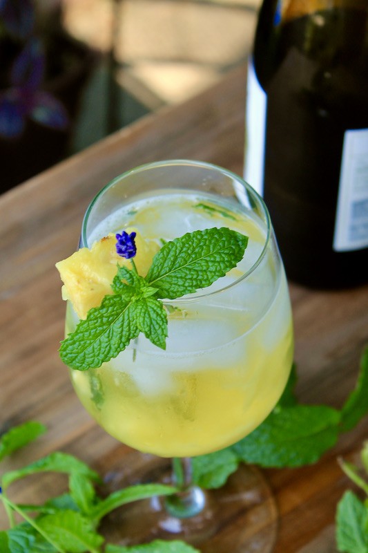 add ice stir and garnish white wine spritzer with pineapple and mint