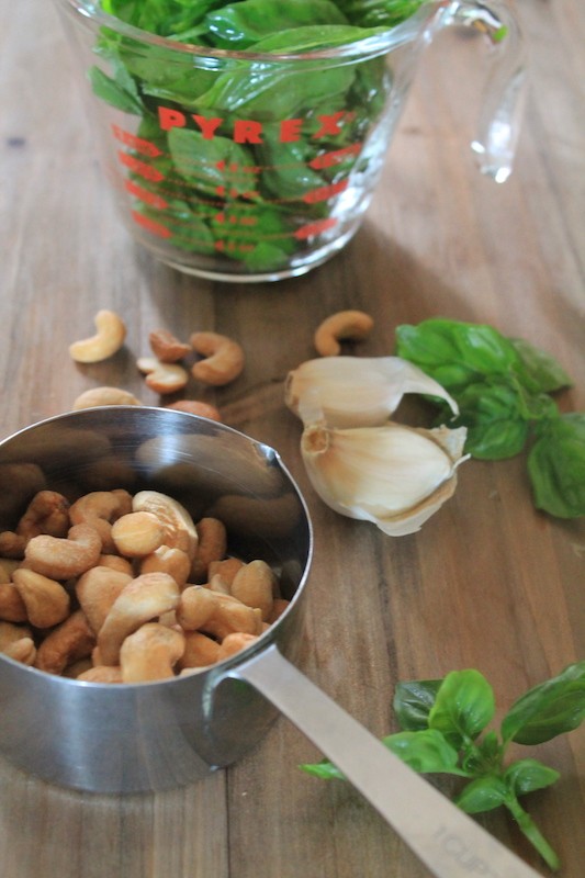 basil pesto ingredients with cashews, garlic, basil, parmesan, and olive oil