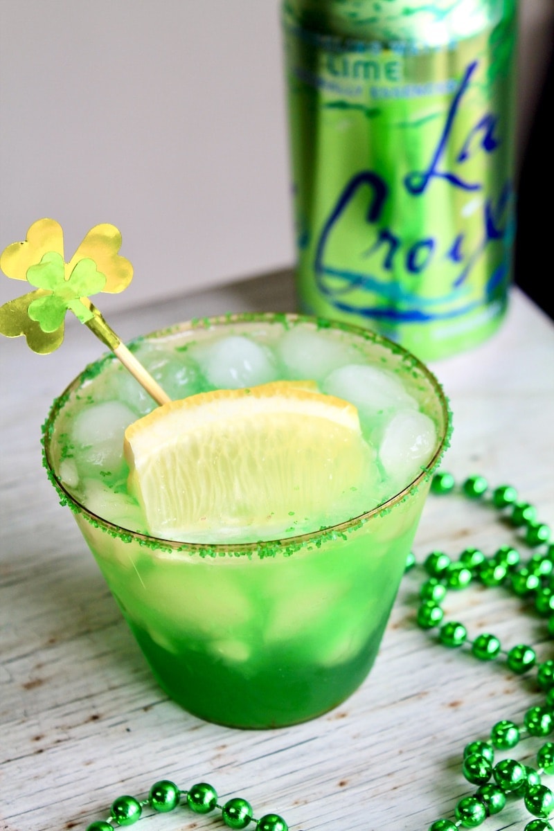 combine  green food coloring lemon vodka simple syrup and apple liqueur in cocktail shaker with ice and shake
