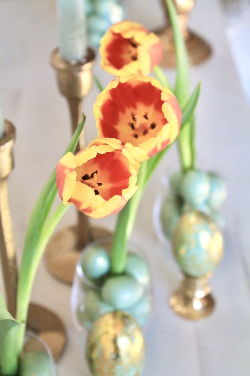 use artificial florals to place in wide stemless wine glasses with small mini easter eggs inside 